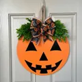 Halloween pumpkin face wooden door sign with decorative green foliage and bow on a white door - Smiling Pumpkin