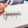 Detail of gold-tone earring set with zircons on white card against blue satin fabric - Large Hoop Earring Set