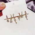 Set of 6 gold earrings featuring star, moon, cross and key charms with white crystals - Key Lock Earring Set