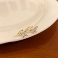 Détail de boucles d'oreilles papillon dorées avec zircons brillants sur une assiette blanche - Or - Grand Clip d'Oreille Papillon