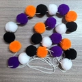 Detail van de Halloween vilten pompon slinger in de kleuren oranje, paars, zwart en wit - Halloween Veelkleurige Viltbal Guirlande