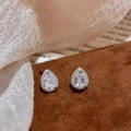 Dettaglio di orecchini a lobo con zircone a goccia su elegante sfondo in velluto marrone - Orecchini a Bottone con Zircone a Goccia