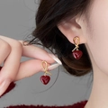 Elegante rote Herzohrringe mit goldenem Knotendesign am Modell für einen stilvollen Look - Roter Herzstil