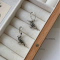 Pendientes de aro cuervo de plata retro con plumas sobre bandeja de joyería beige - Pendientes de Colgante de Cuervo Plateado