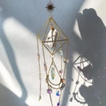 Close-up of geometric wind chime with raw white stone and crystal prisms casting light - White Turquoise