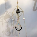 Detail of geometric suncatcher with golden metal frame, amethyst stone and crystal beads - Obsidian