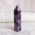 Pointe de cristal d'améthyste hexagonale polie posée sur un livre avec textures - Prisme hexagonal à pointe unique / Violet de Rêve