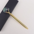 Detail eines goldenen Metall-Kugelschreibers mit rohem Fluorit-Kristall in Geschenkbox - Fluorit