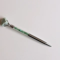 Détail d'un stylo bille argenté avec cristal brut vert et remplissage de pierres assorties - Jade aventurine