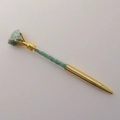 Detail of gold crystal ballpoint pen featuring a green raw gemstone top and crushed stones - Aventurine Jade