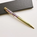 Detail of a gold metal ballpoint pen featuring purple crystal stones in a clear barrel - Amethyst / 14.5cm