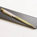 Detailed macro view of golden metal pen filled with pink crystal gravel in a gift box - Rose Quartz / 14.5cm