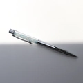 Macro detail of silver metal ballpoint pen with sky blue crystal gravel in transparent tube - Aquamarine