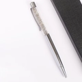 Silver ballpoint pen filled with grey crystal stones next to a black textured gift box - Labradorite