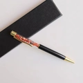 Detail eines schwarzen Kugelschreibers mit roten Kristallsteinen und einer Geschenkbox - Roter Achat