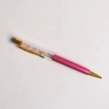 Dettaglio di una penna a sfera rosa con cristalli frantumati e finiture dorate di lusso - Quarzo rosa