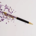 Detail view of a black ballpoint pen filled with purple crystals and gold accents - Amethyst