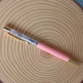 Macro view of crystal fragments inside a pink and gold metallic ballpoint pen on wood - Colorful Fluorite