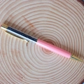 Close-up of a pink crystal ballpoint pen with black stone fillings on a wooden tray - Black Tourmaline