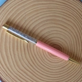 Detailed shot of pink crystal ballpoint pen with gold accents on a wooden background - Labradorite