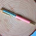 Pink ballpoint pen with turquoise crystal stones and gold accents on wood background - Turquoise