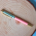 Close-up of elegant pink ballpoint pen filled with green crystal crushed stones - Aventurine Jade