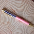 Dettaglio della penna a sfera in cristallo rosa con tocchi dorati su legno - Ametista