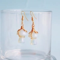 Detail of handmade wire-wrapped mushroom earrings with opal-like stones and gold hooks - Opalite