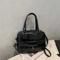 Detailansicht der schwarzen Lackleder-Handtasche mit eleganter Schleife und Metallanhänger - Schwarz