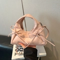Bolso fruncido rosa con lazos y correa fina de hombro en una elegante pose de mano a la moda - Rosa