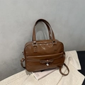 Detail of a brown leather shoulder bag featuring a decorative bow and heart pendant charm - Tan