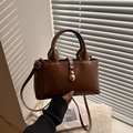 Borsa a mano in pelle marrone con ciondolo dorato e tracolla in luce naturale - Cuoio