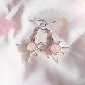 Detail of handmade wire-wrapped sun earrings with pink crystal beads on white fabric - Rose Quartz