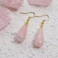 Dettaglio orecchini a goccia in cristallo rosa con ganci dorati su pietra bianca - Quarzo rosa