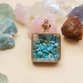 Detailed close-up of square gold pendant filled with turquoise stones on crystal background - Turquoise / 29mm