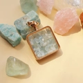 Detail of square gold pendant filled with blue crystal stones on warm beige background - Aquamarine / 29mm