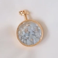 Detailed top view of a gold-rimmed round perfume bottle pendant filled with blue crystals - Angelite / 29mm