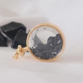Macro shot of circular gold perfume pendant filled with black crystal stones on fabric - Obsidian / 29mm