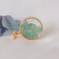 Close-up of golden round perfume pendant filled with natural green crystal stones - Aventurine Jade / 29mm