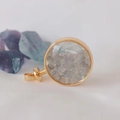 Macro detail of round gold pendant filled with gray labradorite crystal stone chips - Grey Moonstone / 29mm