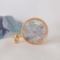 Detailed close-up of a gold round aromatherapy perfume pendant filled with natural crystals - Colorful Fluorite / 29mm