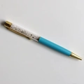 Close-up of sky blue crystal ballpoint pen with gold accents and internal gemstones - Blue Moonstone