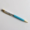 Detail of blue crystal gravel ballpoint pen with transparent barrel and gold metal trim - Angelite