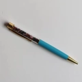 Detailed close-up of blue ballpoint pen with transparent top filled with colorful crystals - Mixed Tourmaline