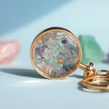 Round golden keychain filled with natural purple and green crystal stones - Colorful Fluorite