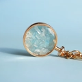 Round golden metal keychain with light blue crystal stones in a wishing bottle design - Kyanite