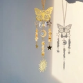Gold sun catcher with butterfly, moon, and crystals casting shadows on a white wall - Citrine