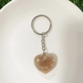 Close-up of translucent heart-shaped stone keychain with silver metal ring and chain - Cherry Blossom Agate