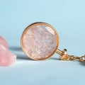 Portachiavi bottiglia dei desideri con cristalli rosa e cornice tonda in metallo dorato - Quarzo rosa