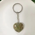 Polished Unakite heart crystal keychain with silver ring on a white plate - Labradorite